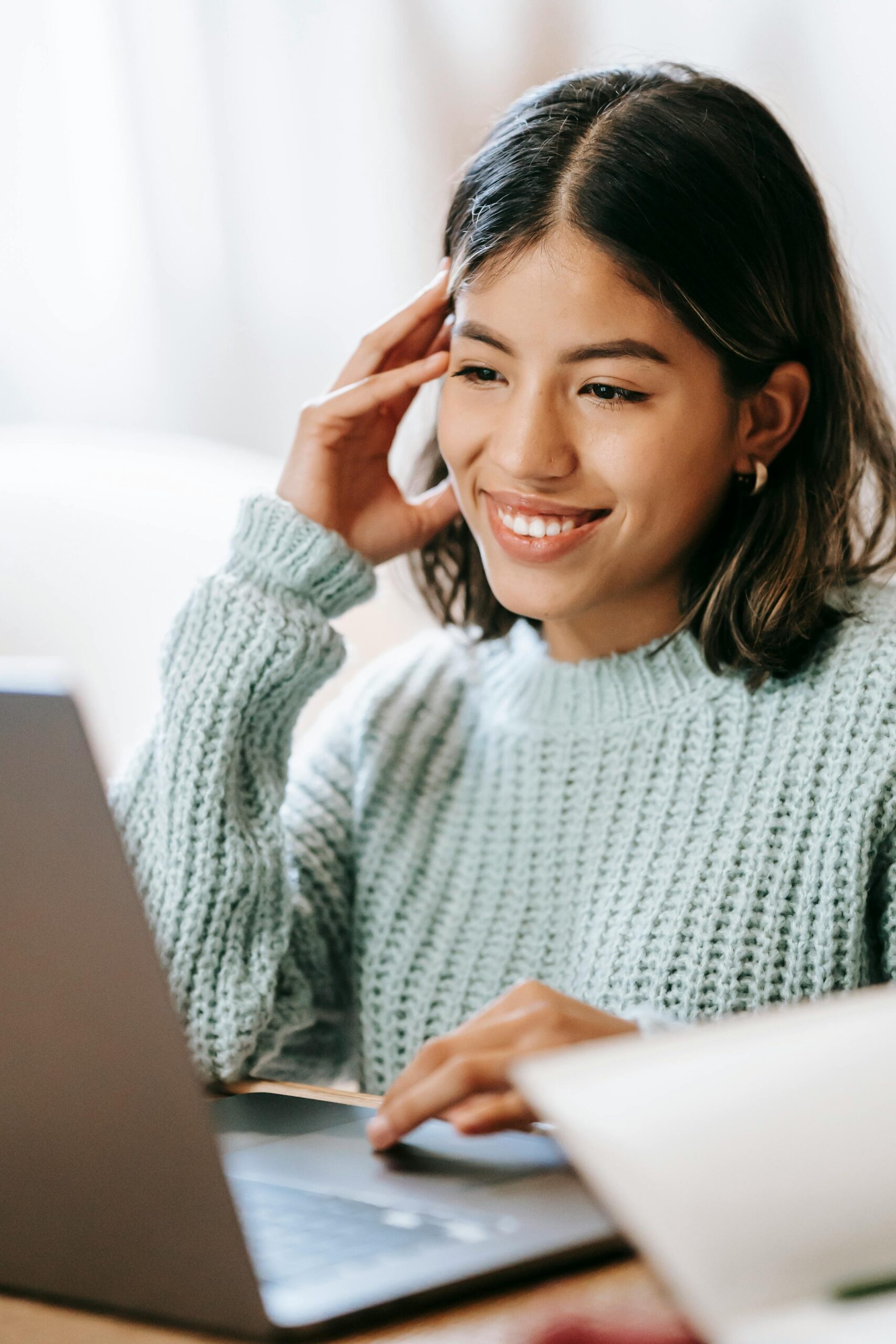young woman in light blue sweater using laptop